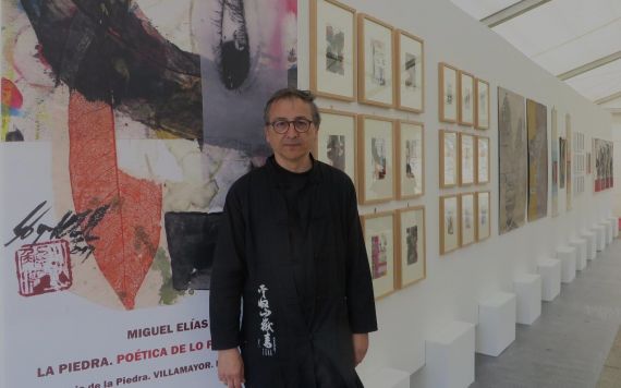 1 Miguel Elías con el cartel de su exposición y parte de la muestra (foto de Jacqueline Alencar)